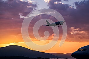 Airplane flying at purple sunset over mountains and sea