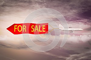 Airplane flying a red banner and text FOR SALE