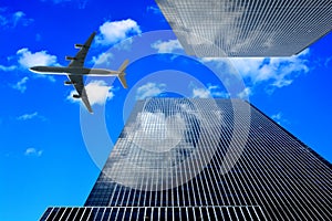 Airplane flying in the sky between two modern architecture skyscrapers