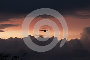 Airplane flying through sunset clouds