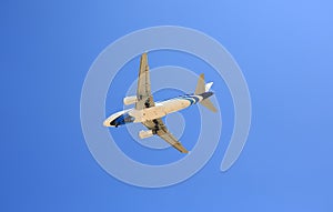 Airplane flying under blue sky. Seen from below