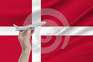 Airplane in hand with national flag of Denmark. Travel to Denmark