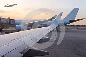 airplane jet waiting to runway on taxi lane in airport and aircraft traffic to take off with sunset background, view from window