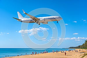 Airplane landing above beautiful beach with people on the beach and sea, travel