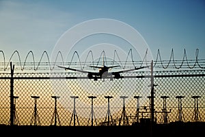 Airplane landing at the airport - sunset landing behind the airport fence