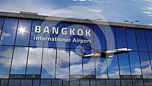 Airplane landing at Bangkok mirrored in terminal