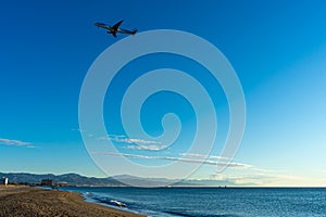 Airplane landing at sunrise over Mediterranean Sea, Costa del Sol in Malaga, Spain on January 21, 2023