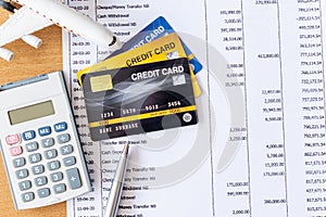 Airplane model and calculator on Bank statement and credit card on a Wooden table. Finance about Travel concept