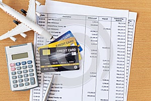 Airplane model and calculator on Bank statement and credit card on a Wooden table. Finance about Travel concept