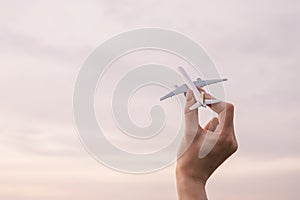 Airplane model in a female hand in the background sky.