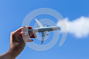 Airplane model in hand on sunny sky. Concepts of travel, transportation