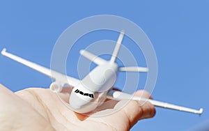 Airplane model in hand on sunny sky. Concepts of travel, transportation