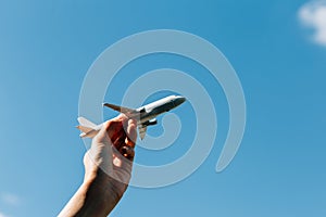 Airplane model in hand on sunny sky. Concepts of travel, transportation