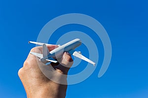 Airplane model in hand on sunny sky. Concepts of travel, transportation, transport, dreaming about holidays.