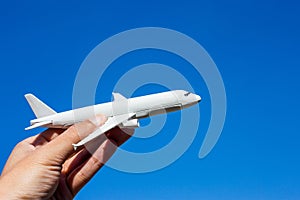 Airplane model in hand on sunny sky. Concepts of travel, transportation, transport, dreaming about holidays.