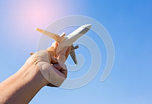 Airplane model in hand on sunny sky. Concepts of travel, transportation, transport, dreaming about holidays.