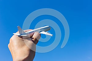 Airplane model in hand on sunny sky. Concepts of travel, transportation, transport, dreaming about holidays.