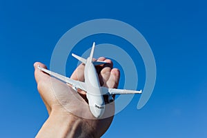 Airplane model in hand on sunny sky. Concepts of travel, transportation, transport, dreaming about holidays.