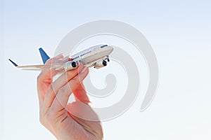 Airplane model in hand on sunny sky. Travel, transportation