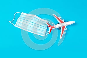 Airplane model with red wings with a blue medical mask. online ticketing and tourism concept during covid pandemic