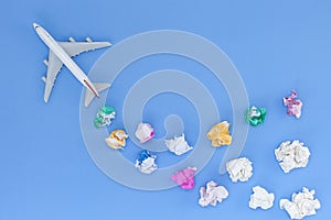 Airplane model with various paper ball on blue background with