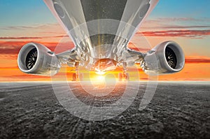 Airplane in the parking lot of the airport apron, bottom view- engines, fuselage and wings. Background of the sky sunset sky cloud