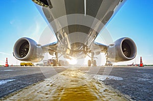 Airplane in the parking lot of the airport apron, bottom view hdr of engines, fuselage and wings.