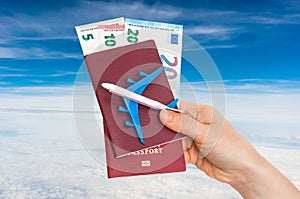 Airplane, passport and money in female hand - travelling concept