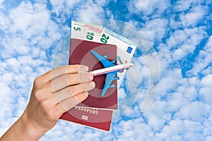 Airplane, passport and money in female hand - travelling concept