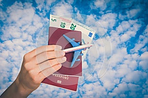 Airplane, passport and money in female hand - travelling concept