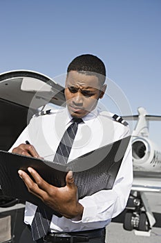 An Airplane Pilot Taking Notes At Airfield photo