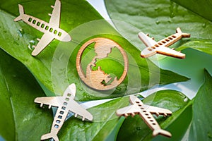 Airplane and planet earth symbol on green leaves, Airplane flight carbon footprint, Wooden airplane icon, Concept of reducing co2