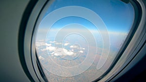 Airplane porthole with the land and the sky seen from it