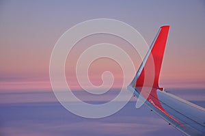 Airplane red wing and winglet, sunrise sky colors