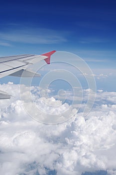 Airplane's wing in blue sky over clouds