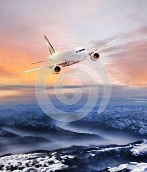 Airplane in the sky over winter Alps at amazing colorful sunset