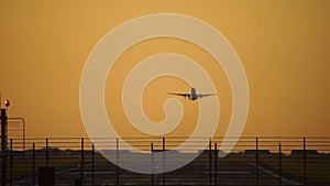 Airplane take off in silhouette against an orange sunset sky