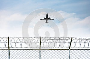 Airplane taking off from the airport over the fence of high security zone