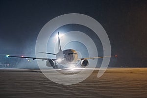 Airplane taxiing at airport during heavy snowfall photo