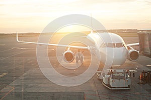 Airplane at the terminal gate. Modern international airport during sunset background