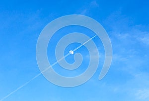 Airplane track crosses the moon in the blue sky. Copy space for text