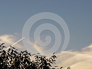 Airplane trail in the blue sky with white clouds