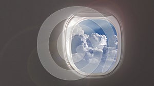Airplane window with 4K video of blue sky cloudy aerial view inside aircraft.