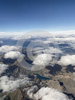 Airplane window skyline view with blue sky and lake clouds. Mountains layers in Italy from airplaneâ€™s window