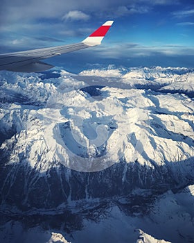 Airplane window view: airliner overflying the swiss-italian Alps