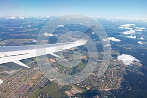 Airplane window view showing wing of the plane flying over small town city