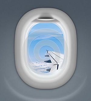 Airplane window with wing and cloudy sky