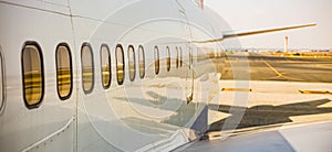 Airplane windows of a jumbo jet parked on the tarmac at an airport