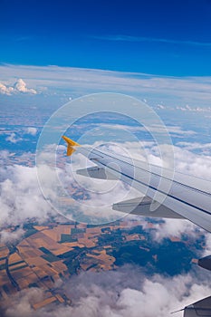 Airplane windows view above the earth on landmark down. View from an airplane window over a wing flying high above farmlands and