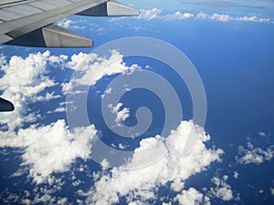 The airplane wing above the blue cloudy sky